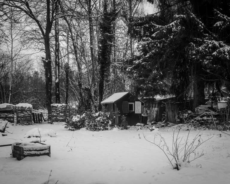 A rustic winter retreat nestled in the quiet charm of a German kleingarten, wrapped in snow’s serene embrace. — Snow dreams of warm fires,      Winter weaves ancient spells.